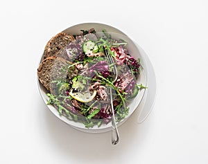 Fresh vegetables, arugula, radicchio salad with canned tuna on a white background, top view. Healthy diet food