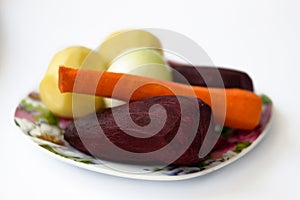 Fresh vegetables beet, carrot, potato, onion on plate on white. Ingredients of healthy lifestyle and proper nutrition