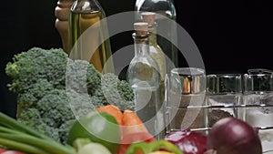 Fresh vegetables, bottles with oil and vinegar, spice jars on the kitchen table