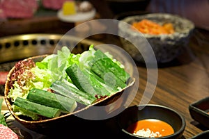 Fresh vegetables in a bowl are placed on the table near the stove. Japanese cucumber, Red oak lettuce and Green Batavia