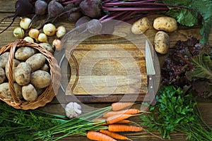 Fresh vegetables from carrot, beetroot, onion, potato on old wooden board. Top view. Copy space on cutting board.