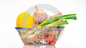 Fresh vegetables in a cart from a supermarket on a white background, natural vegetables lemon, ginger, with herbs in a shopping