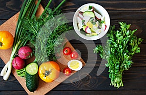 Fresh vegetables on a cutting board with herbs for salad on a dark background. Diet Food Top View