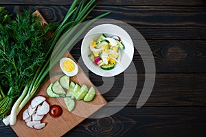 Fresh vegetables on a cutting board with herbs for salad on a dark background. Diet Food Top View