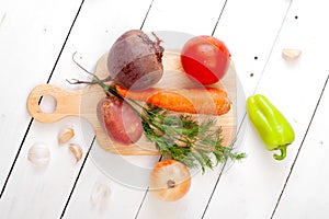 Fresh vegetables on a cutting board - radishes, beets, potatoes, dill, tomato, sweet pepper