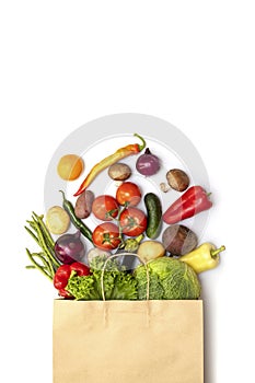 Fresh vegetables in eco friendly paper bag on white background, top view. Food delivery. Grocery shopping. Healthy eating concept