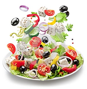 Fresh vegetables and feta cheese falling down into the white plate isolated. File contains clipping paths photo