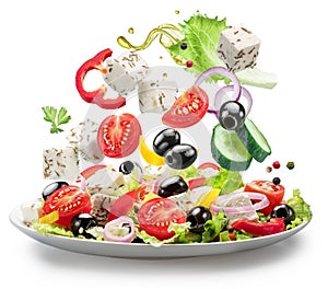 Fresh vegetables and feta cheese falling down into the white plate isolated. File contains clipping paths photo