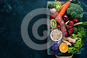 Fresh vegetables and fruits in a wooden box on a black background. Organic food.