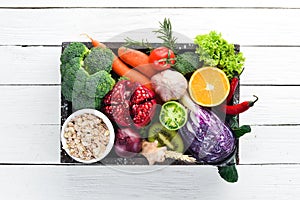 Fresh vegetables and fruits in a wooden box on a white wooden background. Organic food.