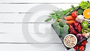 Fresh vegetables and fruits in a wooden box on a white wooden background. Organic food.