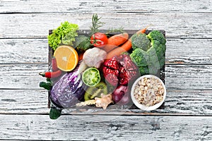 Fresh vegetables and fruits in a wooden box on a white wooden background. Organic food.