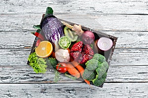 Fresh vegetables and fruits in a wooden box on a white wooden background. Organic food.