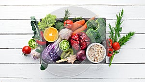 Fresh vegetables and fruits in a wooden box on a white wooden background. Organic food.