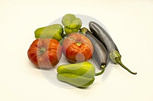 Fresh vegetables from green sweet peppers and  large red tomatoes and black- purple eggplants grown in Armenia lies on a white bac