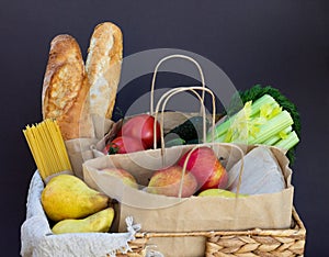 Fresh vegetables, greens and fruits, cereals and pasta in a wicker basket. Delivery or donation of food concept