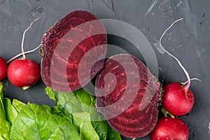 Fresh vegetables and greens radish, spinach, beet on a black background