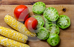 Fresh vegetables including corn, tomato and sliced green tomato