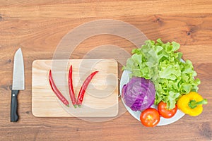 Fresh vegetables and knife on cutting board on wood table photo