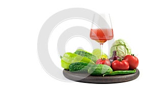 Fresh vegetables in a large assortment with a glass of freshly squeezed juice on a white background with a place to copy