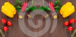 Fresh vegetables like yellow bell peppers, cherry tomatoes, rosemary and parsley leaves. Healthy food frame on wooden background