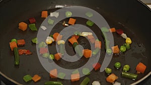 Fresh vegetables with oil frying in a pan. Slow motion and close up. Frozen vegetable mix on frying pan. Vegetables laid