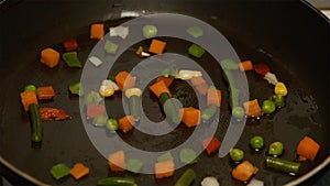 Fresh vegetables with oil frying in a pan. Slow motion and close up. Frozen vegetable mix on frying pan. Vegetables laid
