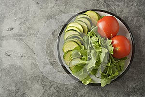 Fresh vegetables in a plate - salad mix, tomatoes and zuchinni. Healthy food concept, lose weight