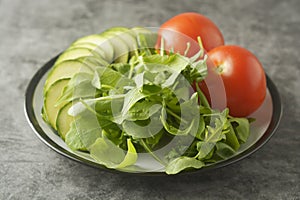 Fresh vegetables in a plate - salad mix, tomatoes and zuchinni. Healthy food concept, lose weight