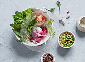 Fresh vegetables - radishes, tomatoes, garden herbs and green peas and chickpeas on a light blue stone background.
