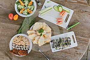 Fresh vegetables with salad and grilled sausages on a wooden table background