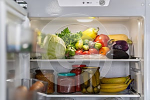 fresh vegetables on the shelf of the open refrigerator in close-up. Many different fresh products in modern refrigerator