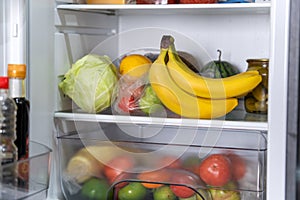 fresh vegetables on the shelf of the open refrigerator in close-up. Open fridge full of fresh fruits and vegetables