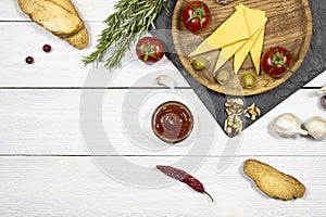 Fresh vegetables, spices and herbs, hot sauce and cheese in a wooden plate on a white wooden background. Free space