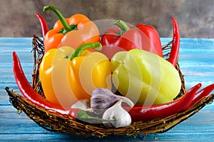 Fresh vegetables,.Sweet red, yellow, green, orange pepper in basket on wooden background. Red pepper spice and black pepper