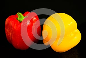 Fresh vegetables Two sweet yellow and red peppers on a black background.Close-up.