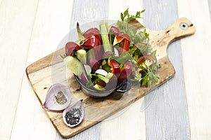 Fresh vegetables on a wooden plate. Red pepper, tomato, cucumber, radish, parsley, dill healthy diet.