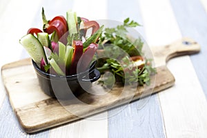 Fresh vegetables on a wooden plate. Red pepper, tomato, cucumber, radish, parsley, dill healthy diet.