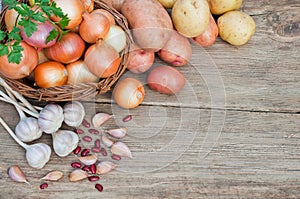 Fresh vegetables on a wooden table: onions, potatoes, garlic