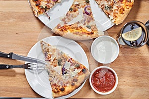 Fresh vegetarian pizza with capers, onions and parmesan and black olives on wooden table in restaurant.