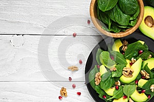 Fresh vegetarian salad with avocado, spinach, pomegranate and walnuts in black plate. healthy food