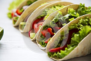 Fresh vegetarian tacos on white wooden background. Closeup.