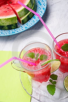 Fresh vegetarian watermelon  cocktail in transporant cups on white table with fresh  watermelon,  lime, melissa. close up