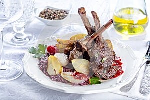 Fresh venison rack on festive table on white plate.