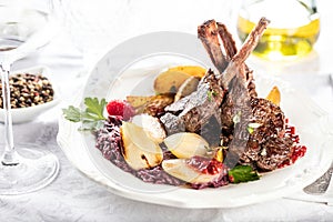 Fresh venison rack on festive table on white plate.