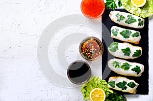 Fresh Vietnamese, Asian, Chinese food frame on white concrete background. Spring rolls rice paper, lettuce, salad