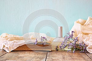 Fresh vintage perfume bottle next to aromatic flowers on wooden table. retro filtered image