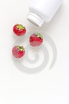 Fresh vitamins as strawberries from medicine white pill bottle on white background