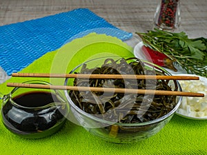 Fresh wakame seaweed in a bowl. Soaked green wakame seaweed in a glass bowl. Japanese food. Eat seaweed with chopsticks