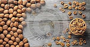 Fresh walnut kernels and whole walnuts in a bowl on rustic old wooden table.